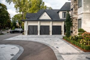 3 car garage with asphalt driveway and beige stone pavers